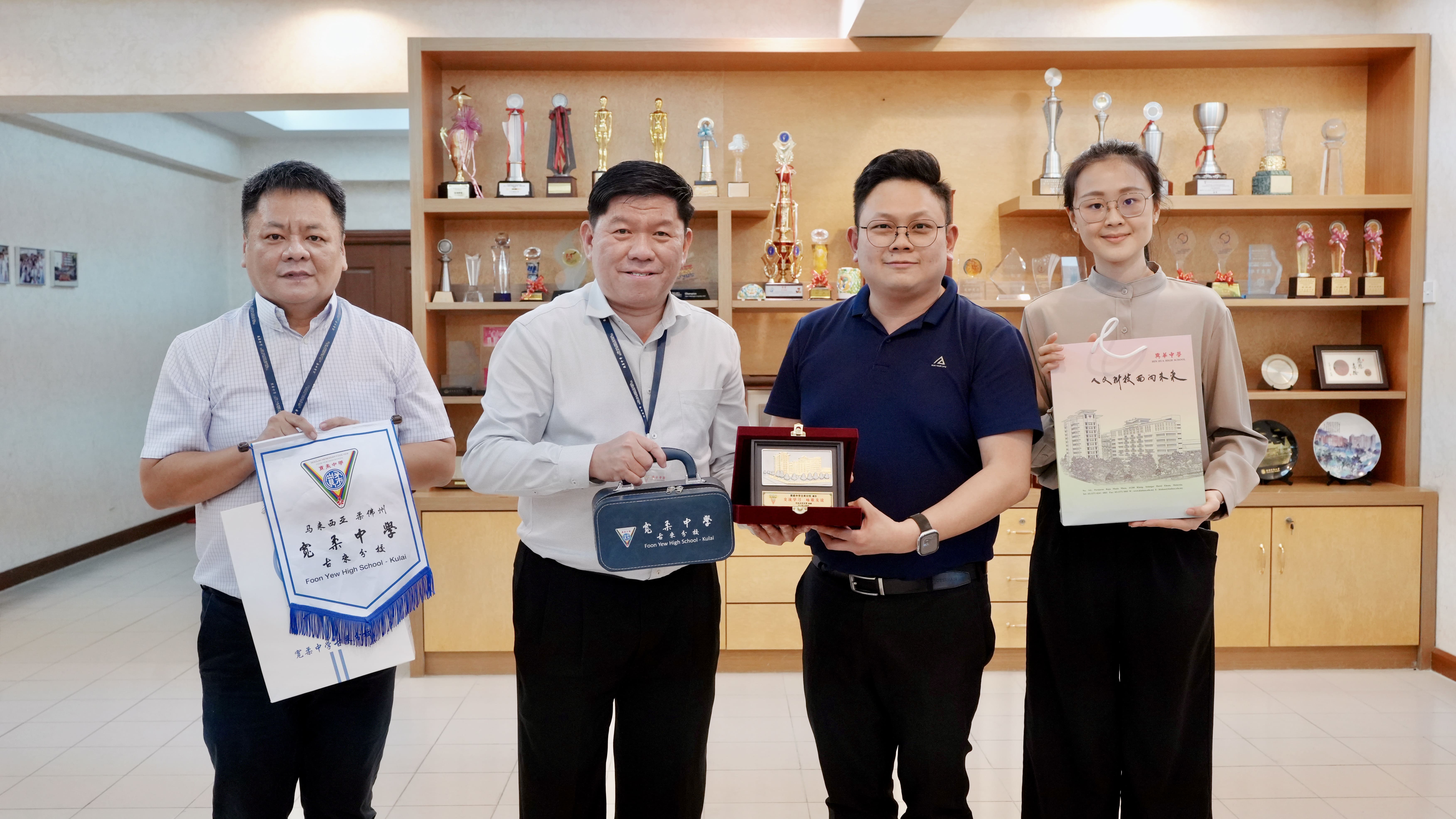巴生兴华中学校长苏进存（左二）及升学与国际事务处主任李辉祥（左一）代表学校接待；宽柔中学古来分校升学辅导处主任符祥靖（右二）与助理主任林俐彤（右一）互赠纪念品，并合照留念。