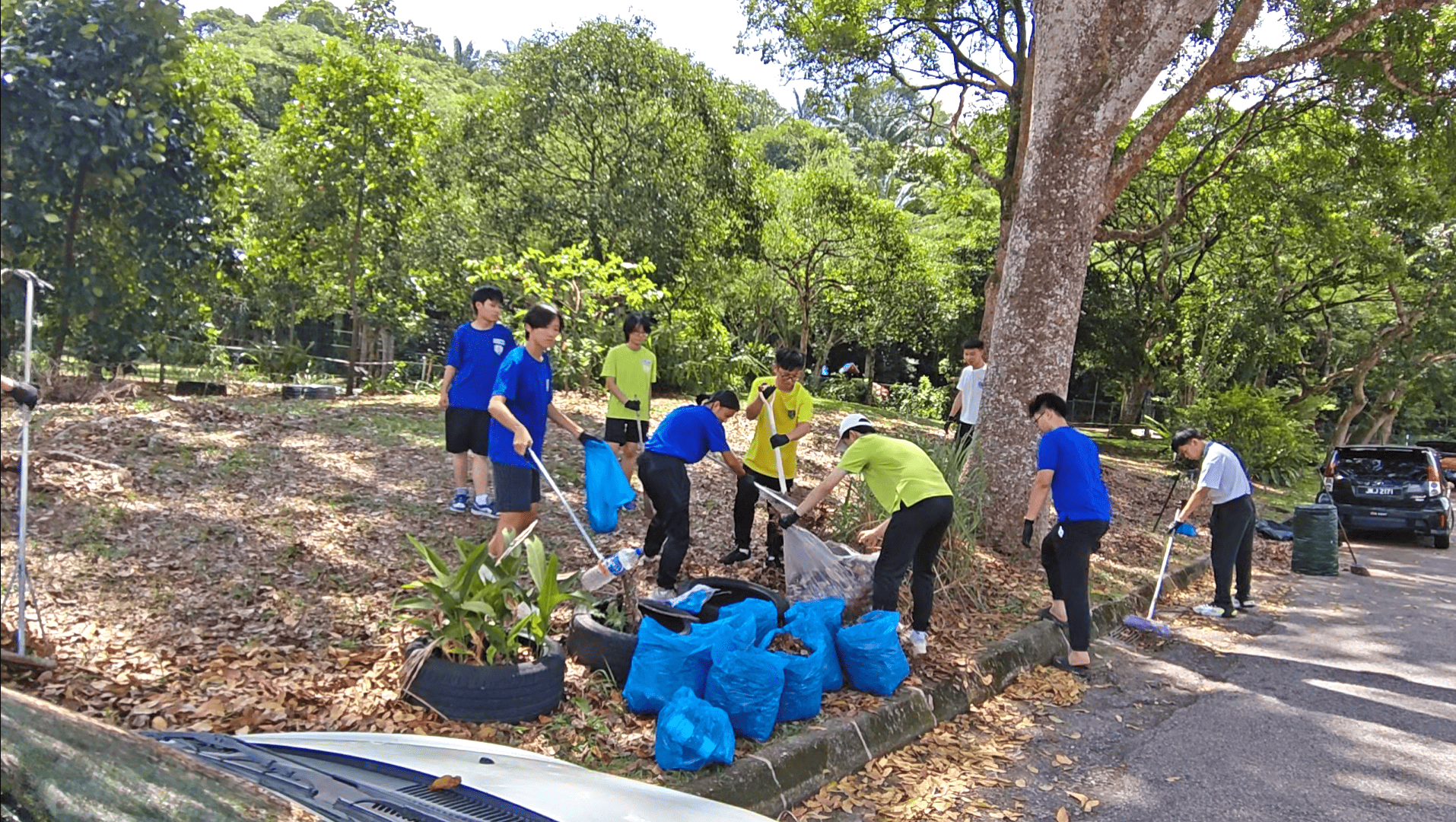 学生们穿戴手套，仔细处理步道、凉亭、草坪及游乐区周边的垃圾。